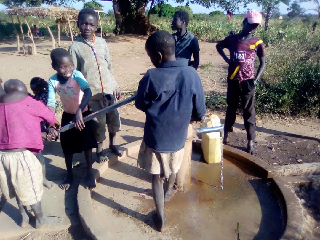 children pumping water at the well