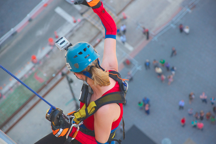 Woman in spiderman costume rappelling down building