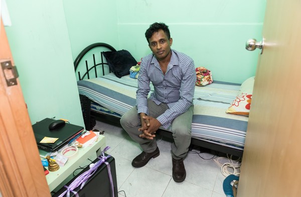 Ajith sitting in his tiny one room apartment in Hong Kong