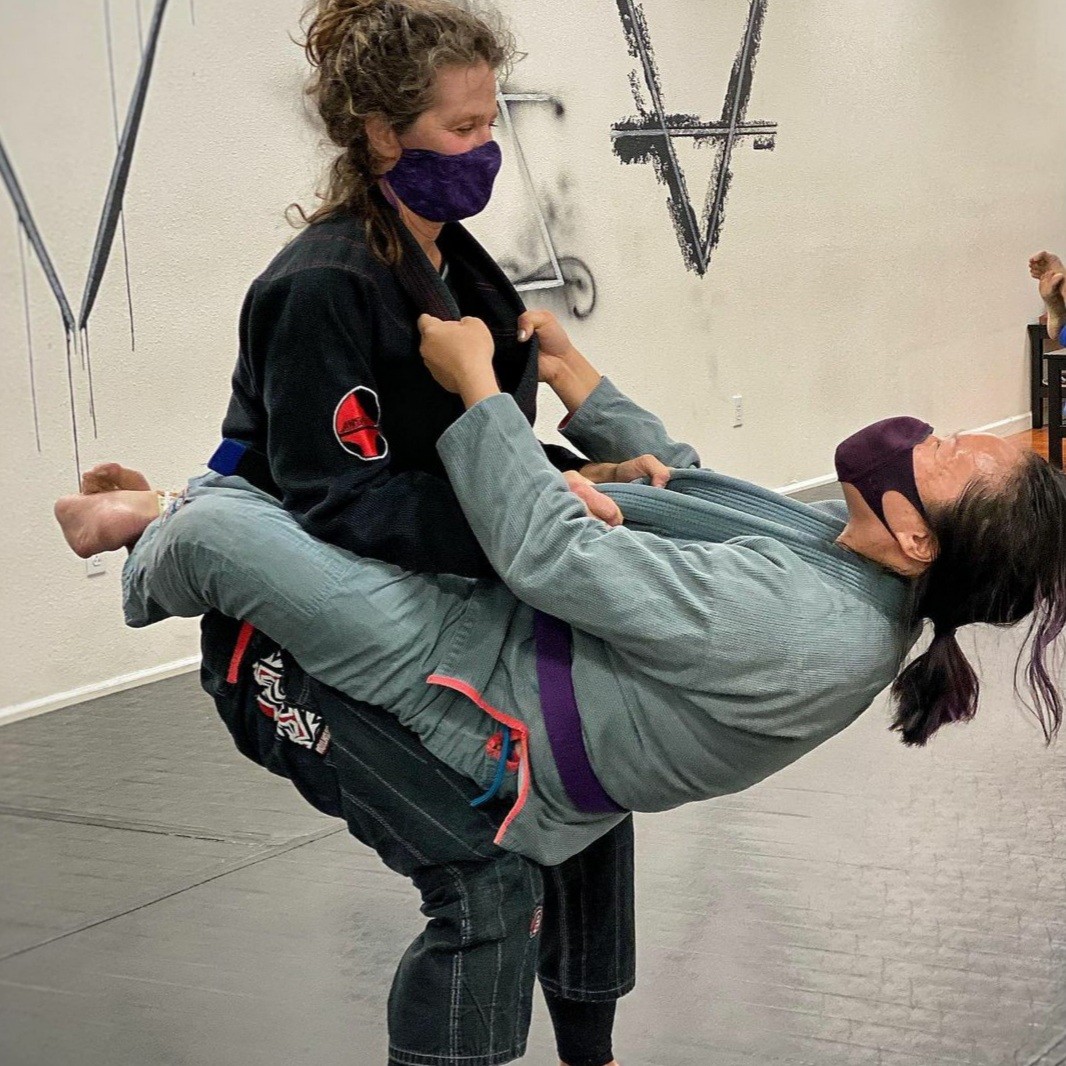 two women practice a Brazilian jiu-jitsu drill