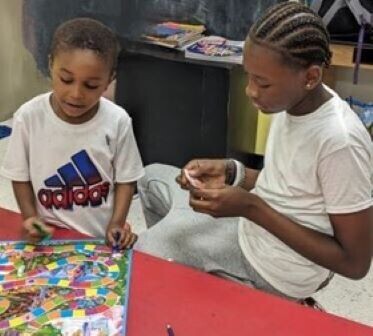 a teen boy playing Candyland with a young boy