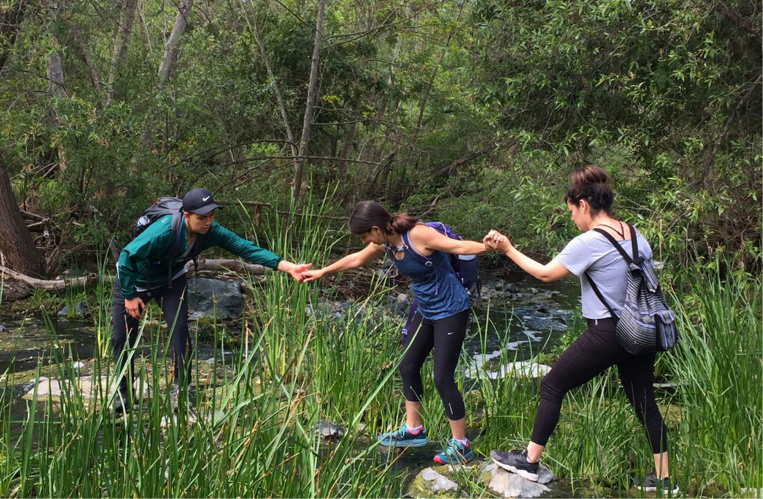 LO Participants giving each other hand crossing a creek