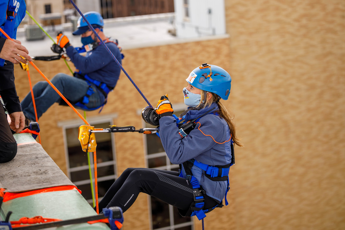Two people rappelling off a building.