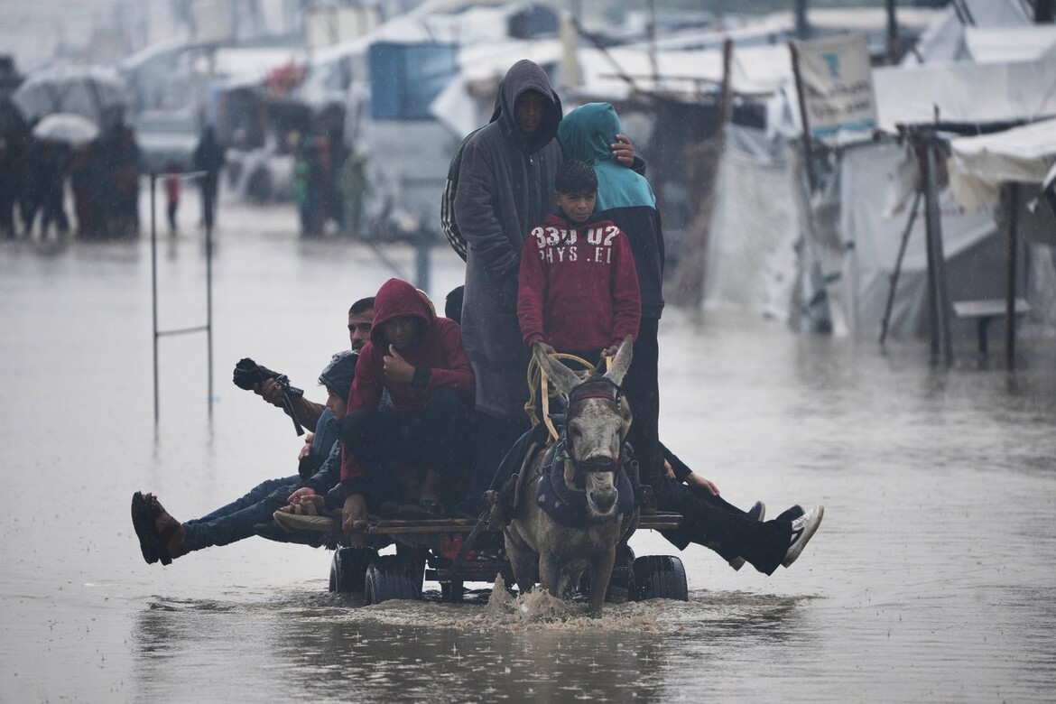 Palestinians cross a flooded street following heavy rain in Khan Younis, southern Gaza Strip