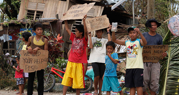 Children hold signs asking for help and food along the highway, after Typhoon Haiyan hit. Photo: Reuters