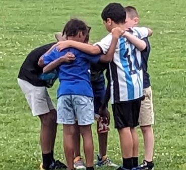 boys in a huddle on a soccer field