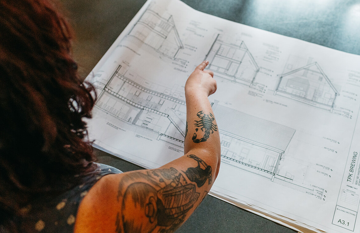 A photograph of a woman pointing at the architectural drawings being used for the permitting process.
