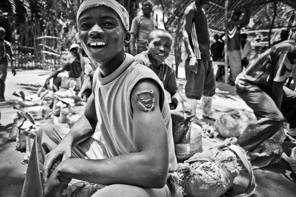 Some diggers are waiting with their minerals at the market of Ndjingala, DRC. The young man has the sign of the tiger on his arm, a symbol of Congo. Foto: Jan-Joseph Stok
