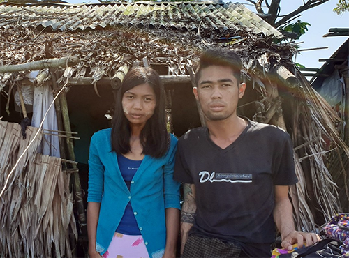 Min Thet (right) with his wife by their current house