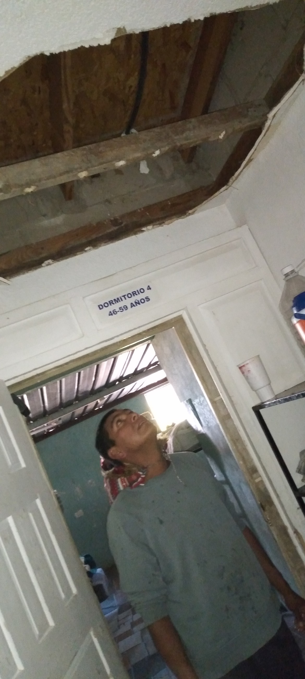 Cesar looks up at a hallway area upstairs that was devastated to the point of falling in.