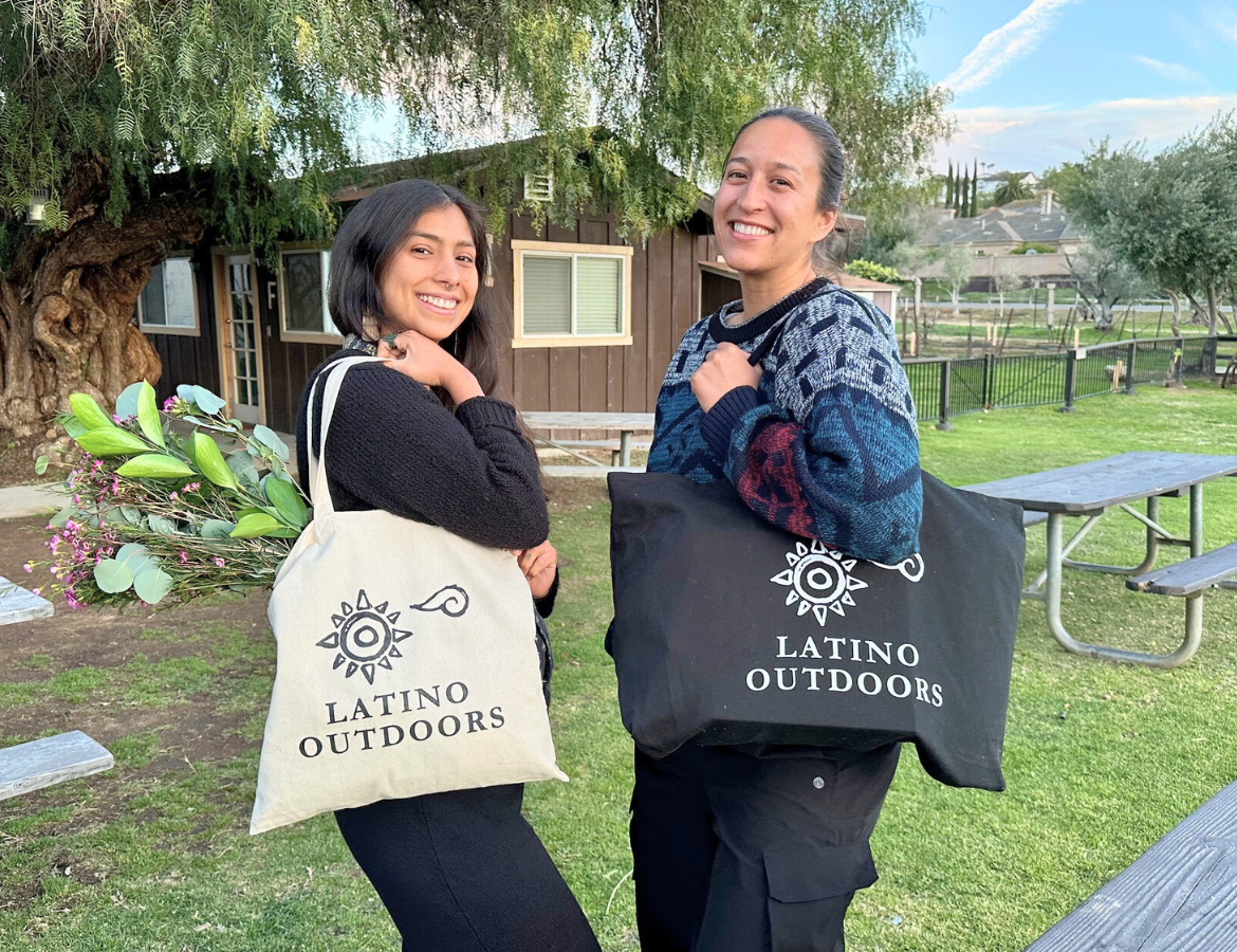 Two people each holding an LO tote