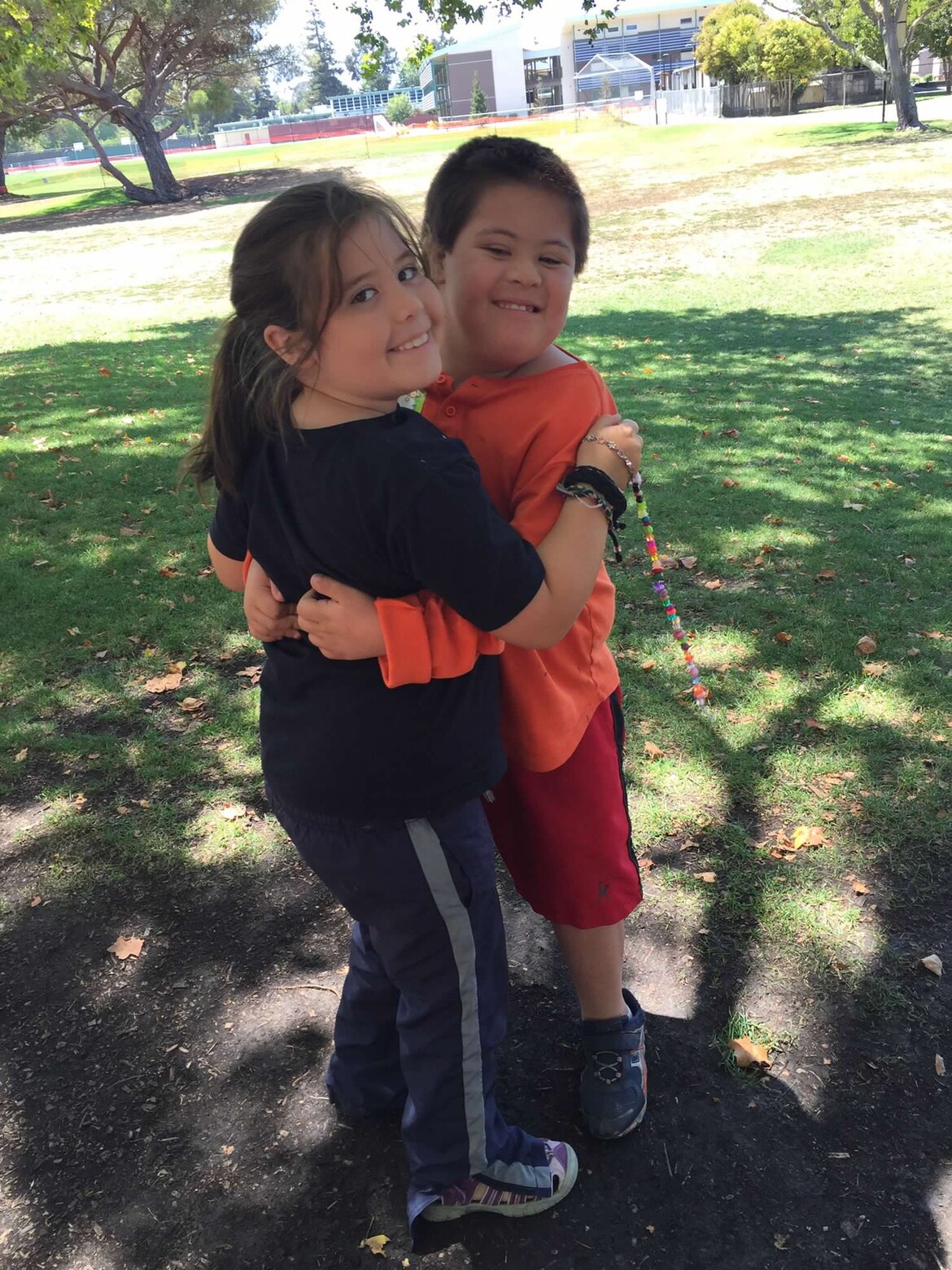 Boy with Down syndrome and girl hugging at the park