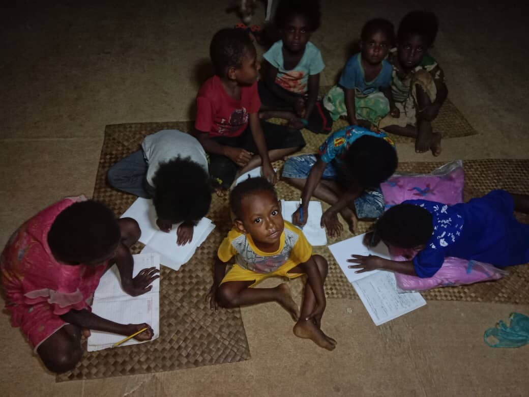 Children studying under the dim glow of lantern light