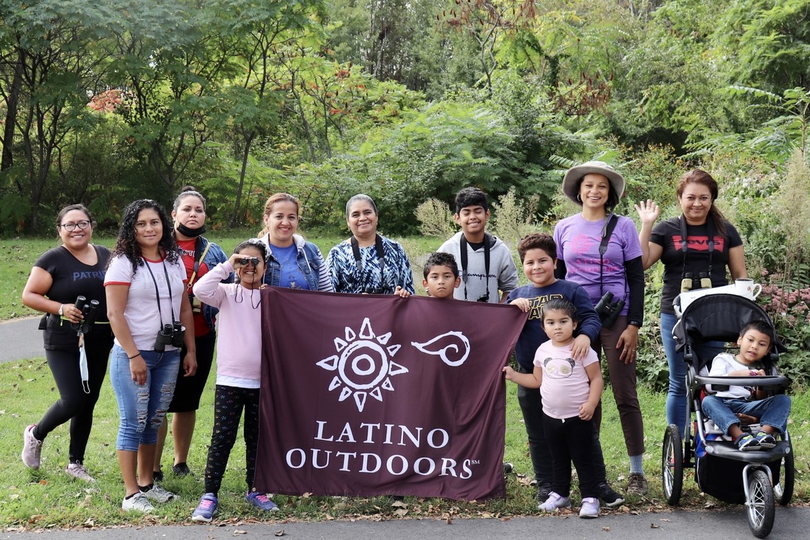 Mothers and children behind a Latino Outdoors banner.