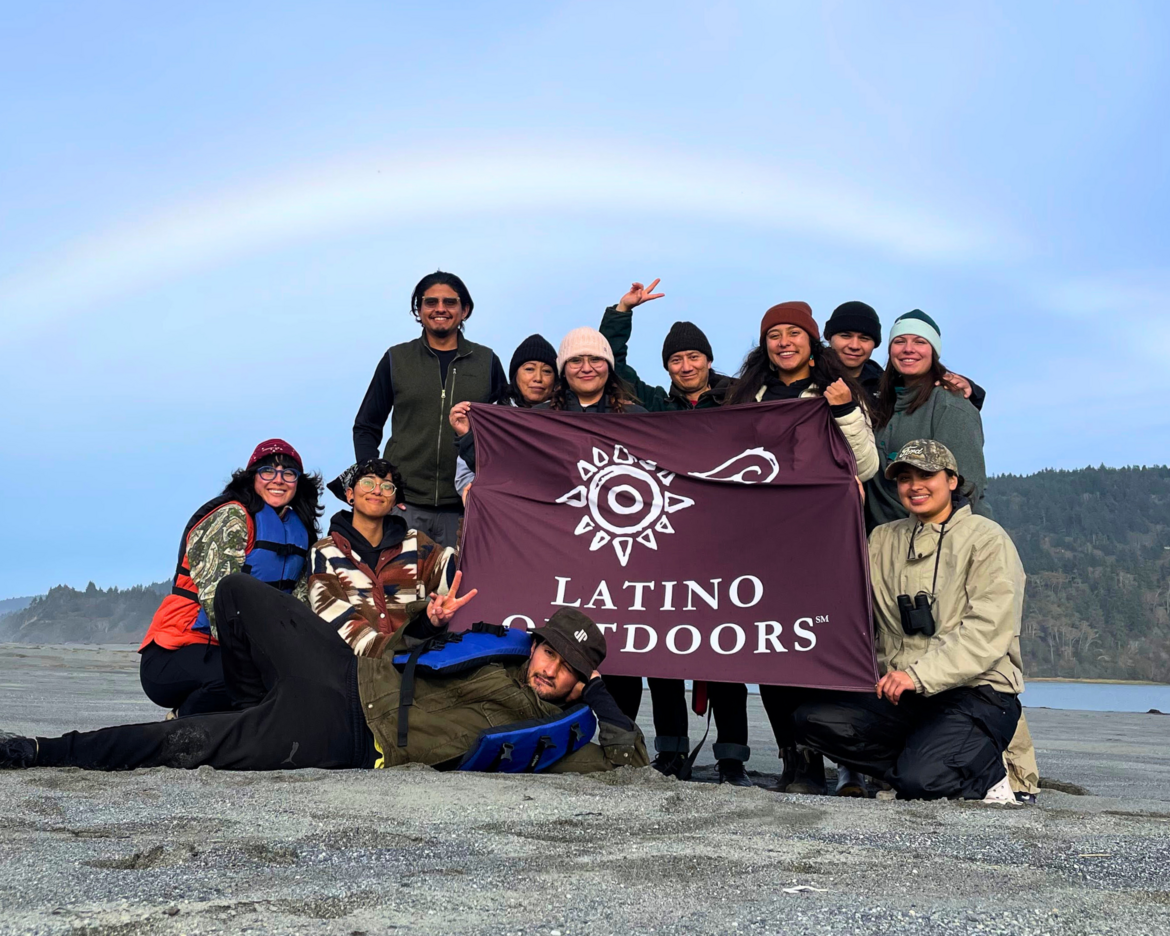 LO participants holding up an LO banner with a rainbow in the background