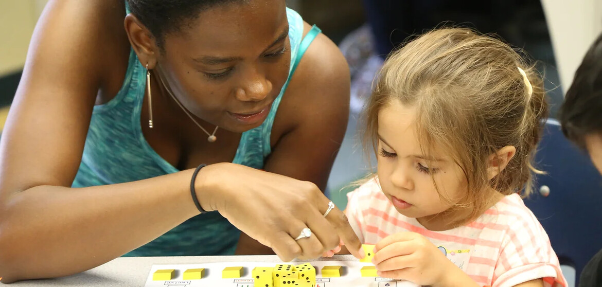 a youth helping a young child with math manipulatives