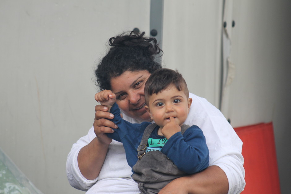 Mother and child in a refugee camp, waving at the camera